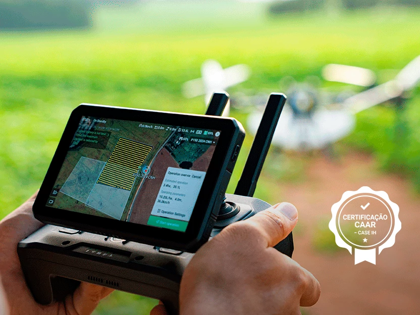 Operador segurando o controle de um drone agrícola Case IH, com o aplicativo de planejamento de voo na tela e o drone pulverizando a lavoura ao fundo, com o selo de Certificação CAAR Case IH