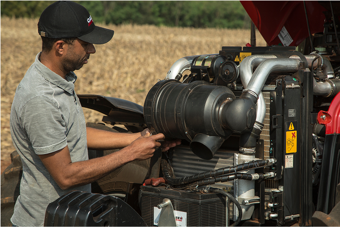 Treinador da Case IH realizando treinamento presencial, demonstrando ajustes e peças dentro do motor de um trator Farmall